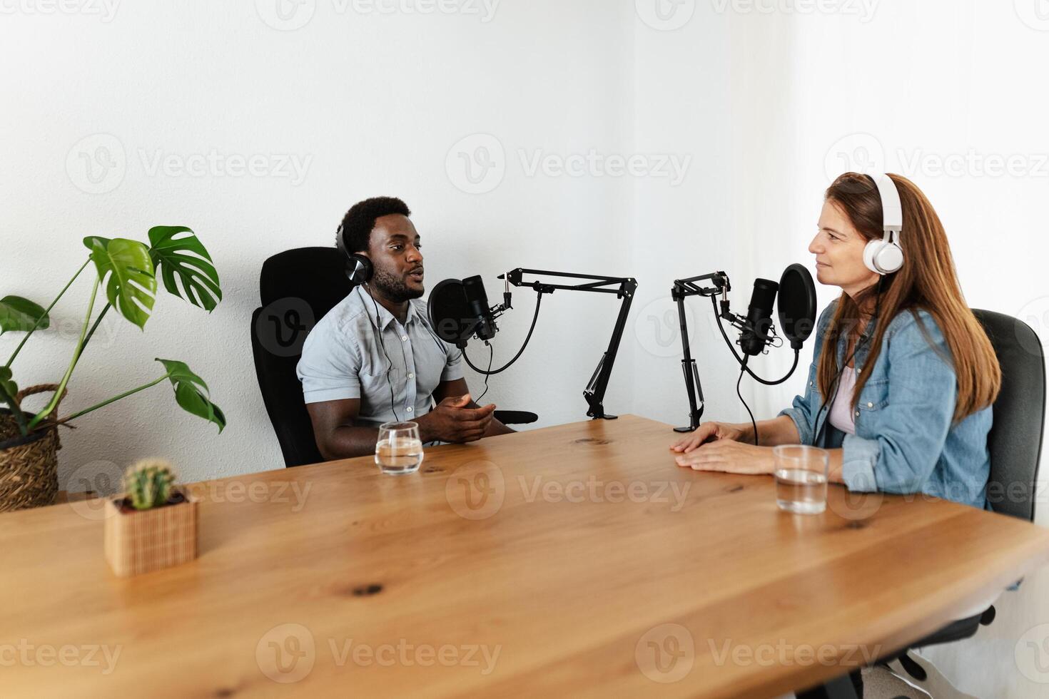 Multiracial people recording a podcast using microphone and headphones from home studio photo