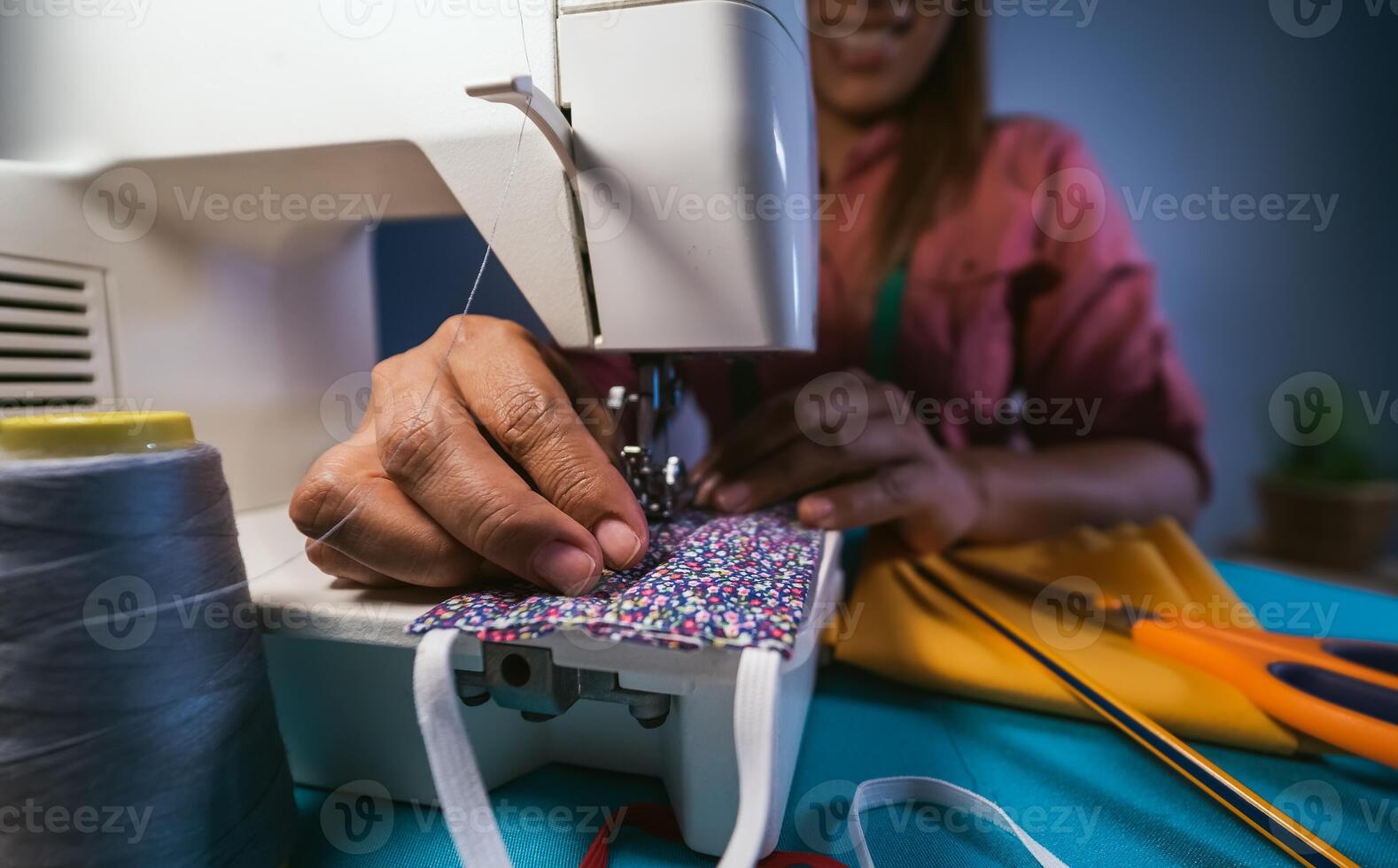 Woman working with sewing machine doing homemade medical face mask for preventing and stop corona virus spreading - Textile seamstress and healthcare concept photo