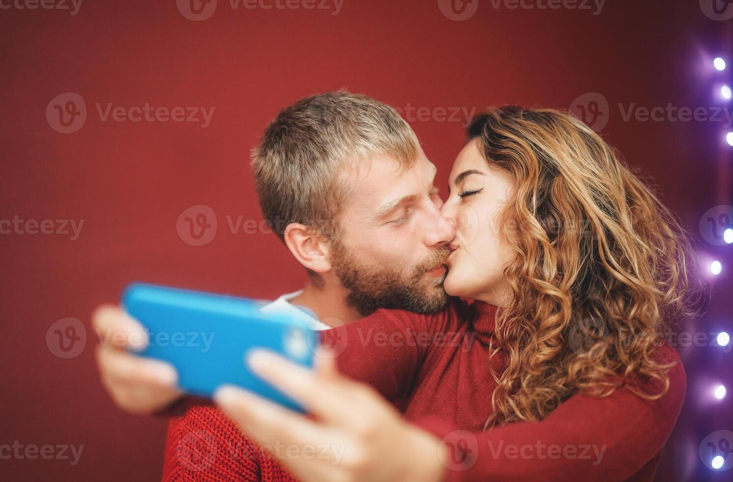 Happy couple making a selfie with mobile smartphone app - Young lovers having fun taking selfie with phone camera - Relationship, love and technology trends concept photo