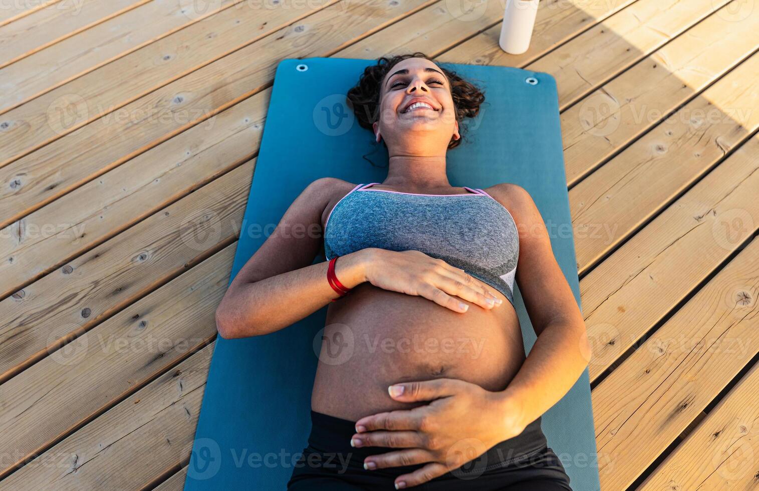 Top view of happy pregnant woman caressing her belly outdoor - Health lifestyle and maternity concept photo