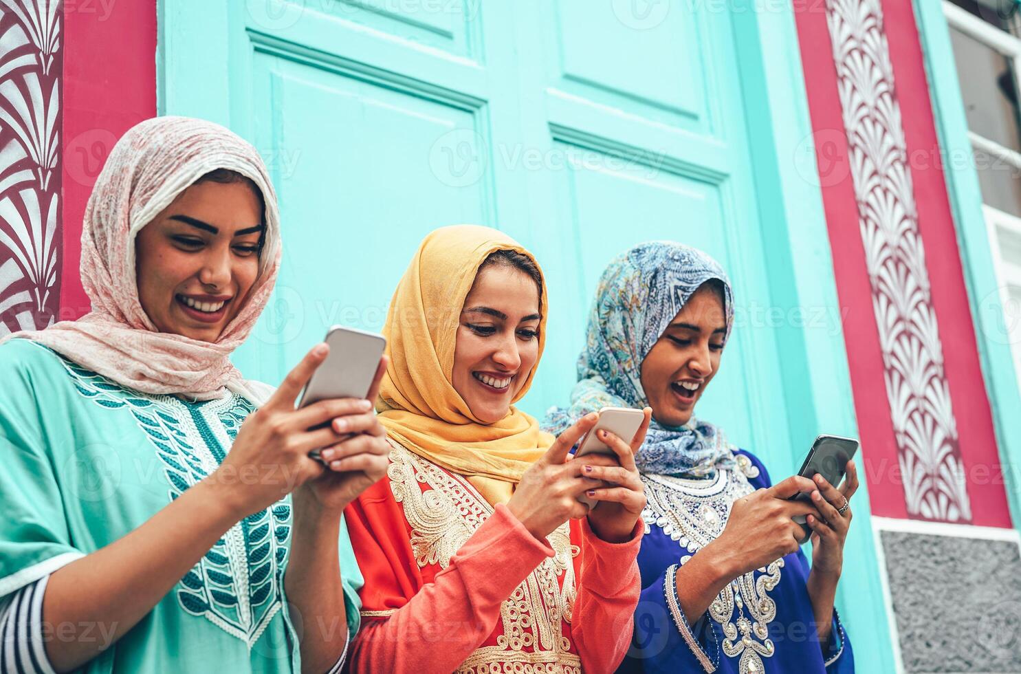 Young Muslim friend using mobile smartphones in the college - Happy Arabian girls addicted to new technology app cellphone for social media - Millennial, religion, generation z and technology concept photo