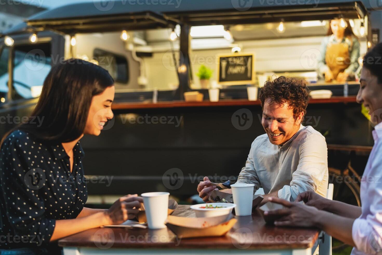 Happy multiracial people having fun eating in a street food truck market photo