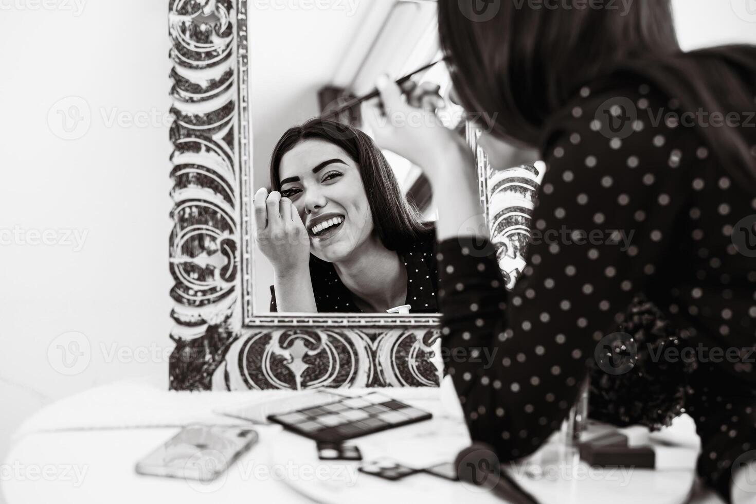 Young woman applying makeup in front of mirror - Cosmetic and lifestyle people concept - Black and white editing photo