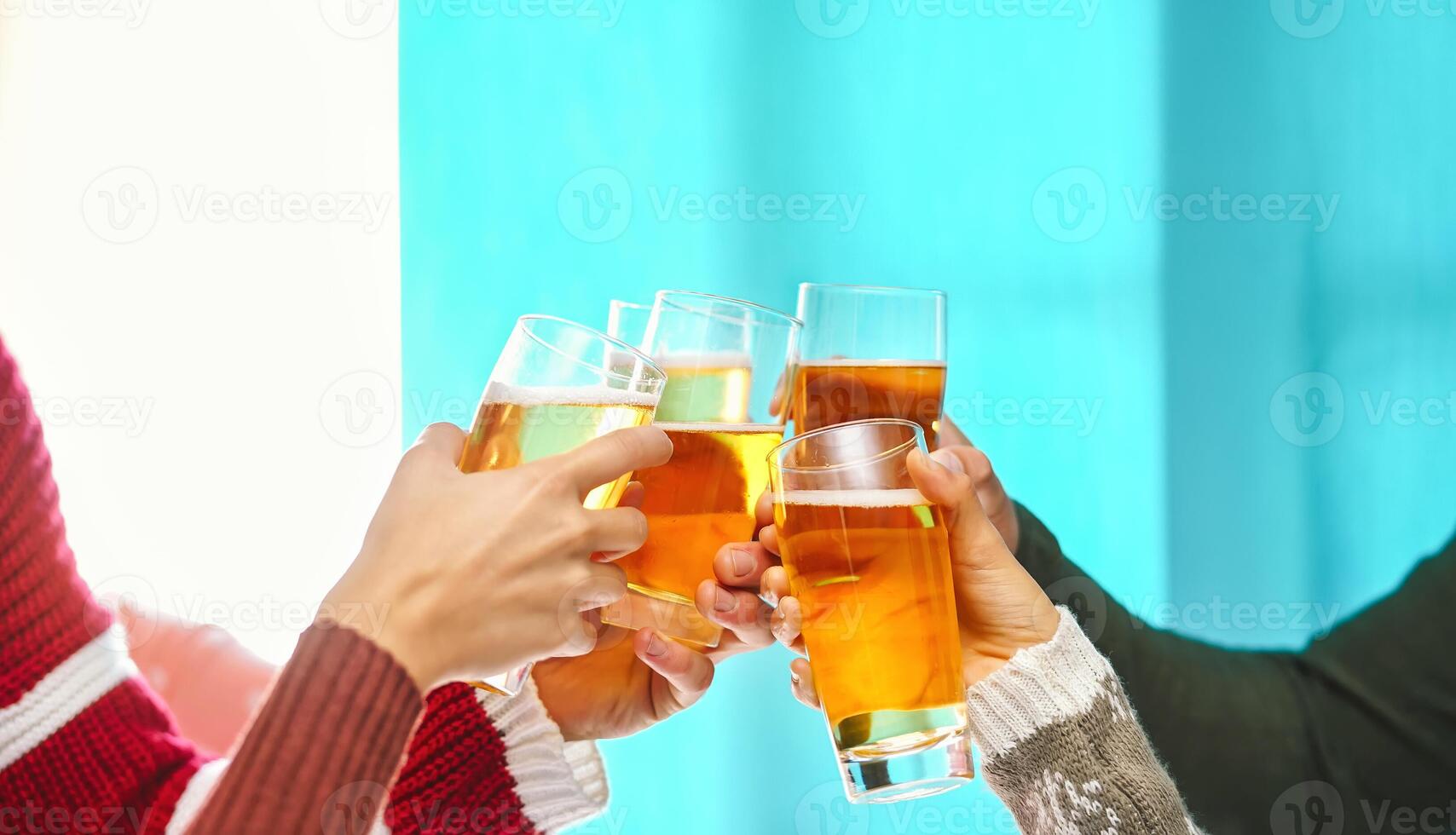 Happy friends doing celebratory toast in winter Christmas holidays - Young people drinking beer in xmas time - Youth culture lifestyle and traditional event celebration concept photo