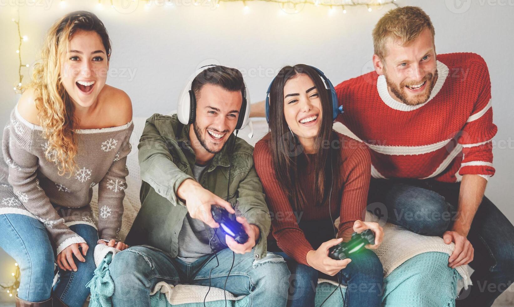 Happy friends playing video games online with headset - Young people having fun with new trendy technologies console gaming - People entertainment and youth millennial generation lifestyle concept photo