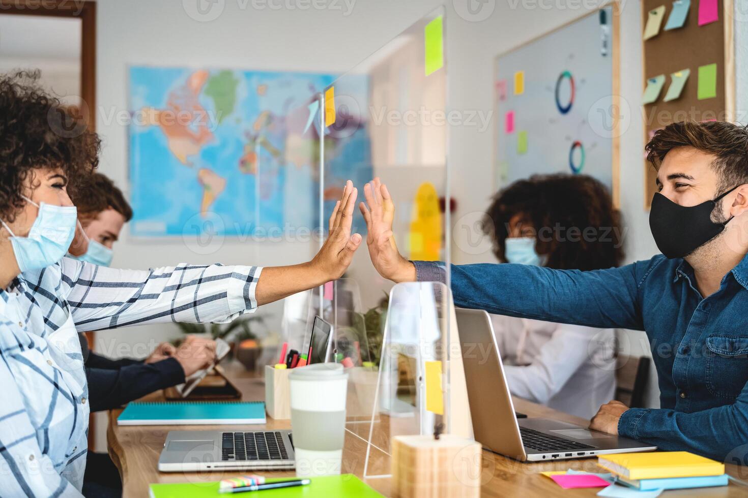 Young people working inside co-working creative space using face protective mask and keeping social distance - Safety work and business concept photo