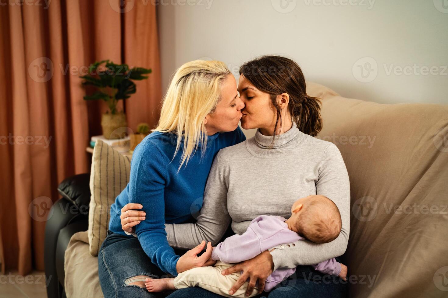 Happy lesbian couple having tender moments with their small baby at home - Family and materhood concept photo