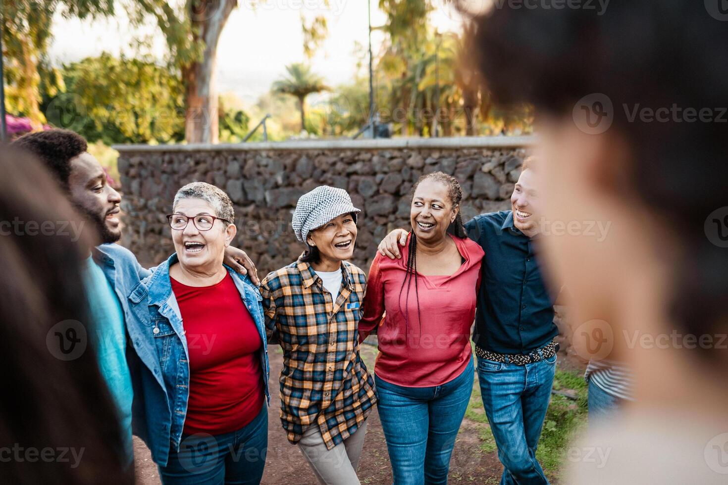 Happy multigenerational group of people with different ethnicities having fun in a public park - People diversity concept photo