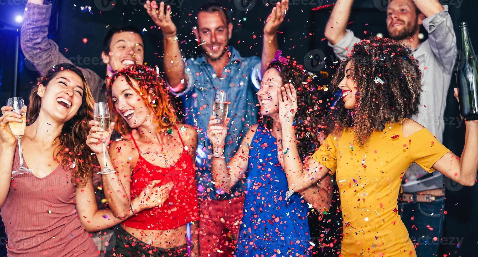 Happy friends doing party dancing and drinking champagne at nightclub - Millennial young people having fun celebrating together and throwing confetti - Entertainment, youth lifestyle holidays concept photo
