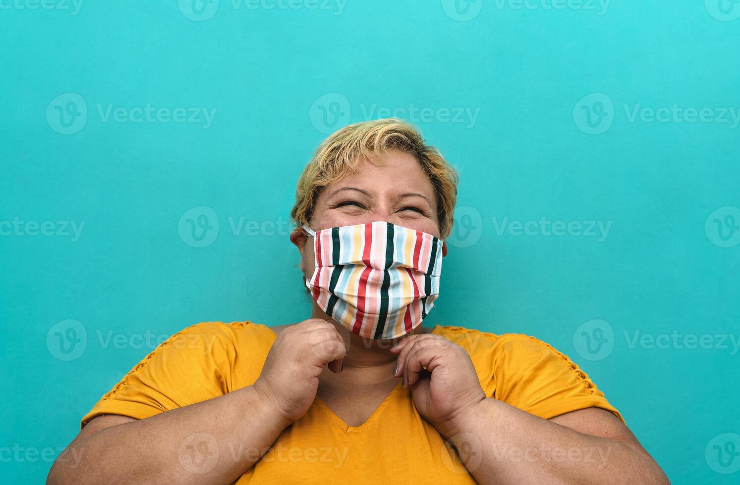 Happy plus size woman wearing face mask portrait - Curvy overweight model having fun posing in front camera - Over size confident person concept photo