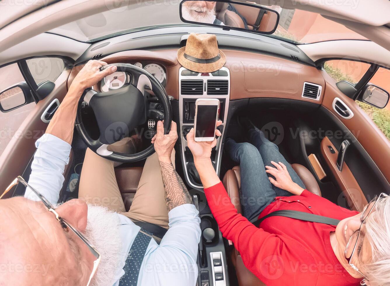 Happy senior couple having fun on new convertible car - Mature people enjoying time together during road trip vacation - Elderly lifestyle and travel transportation concept photo