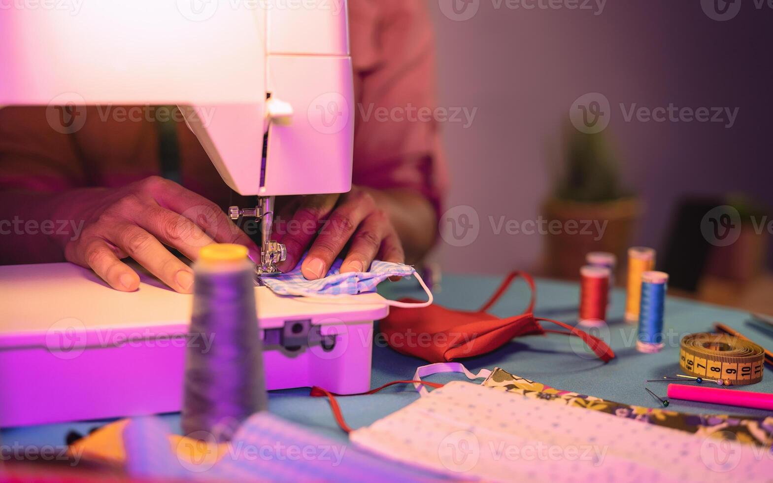 Close up female worker hands working with sewing machine making face medical mask for preventing and stop corona virus spreading - Homemade manufacturing concept photo