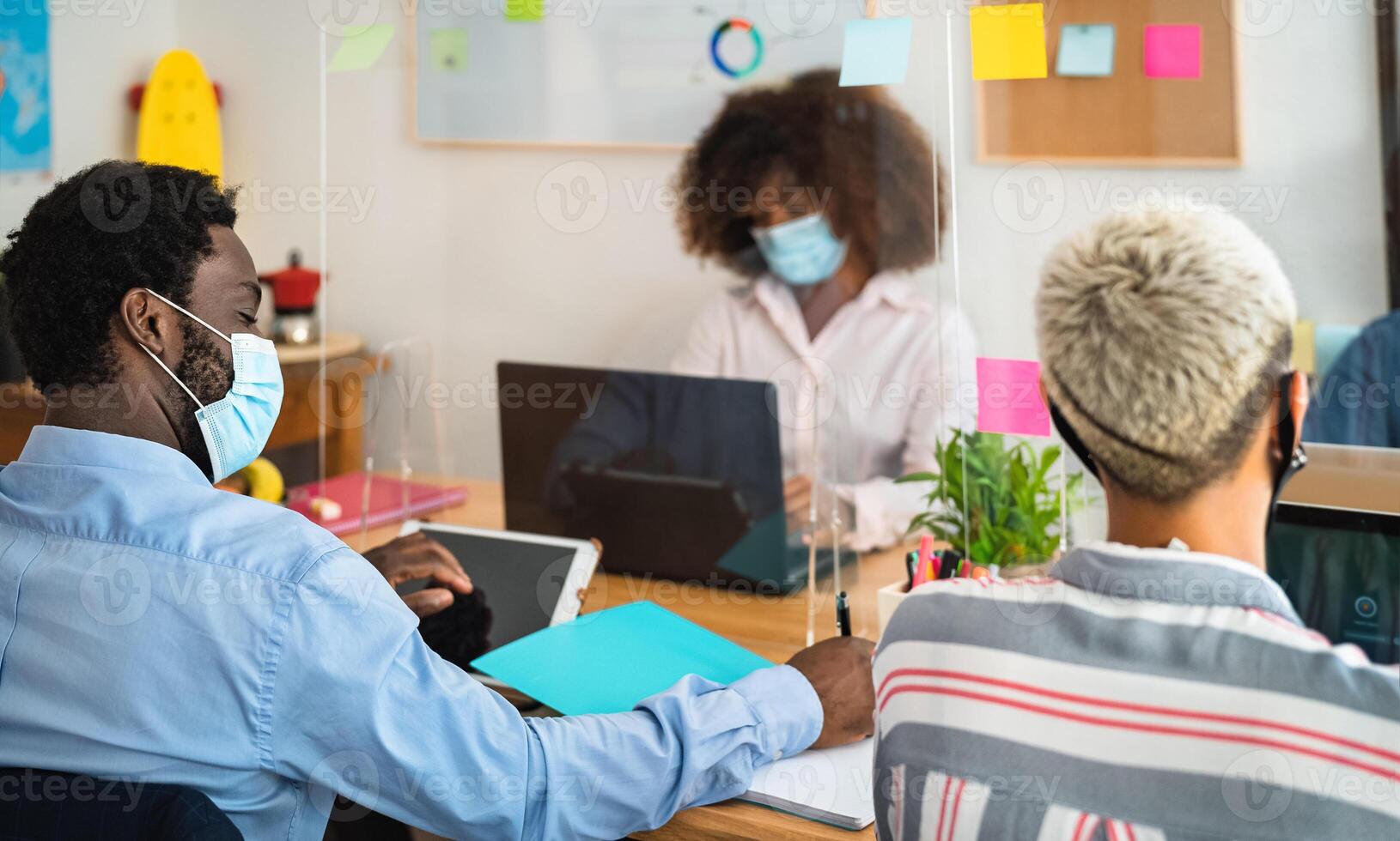 Young people in co-working creative space wearing surgical mask and keeping social distance to avoid corona virus spread - Health care and business technology concept photo