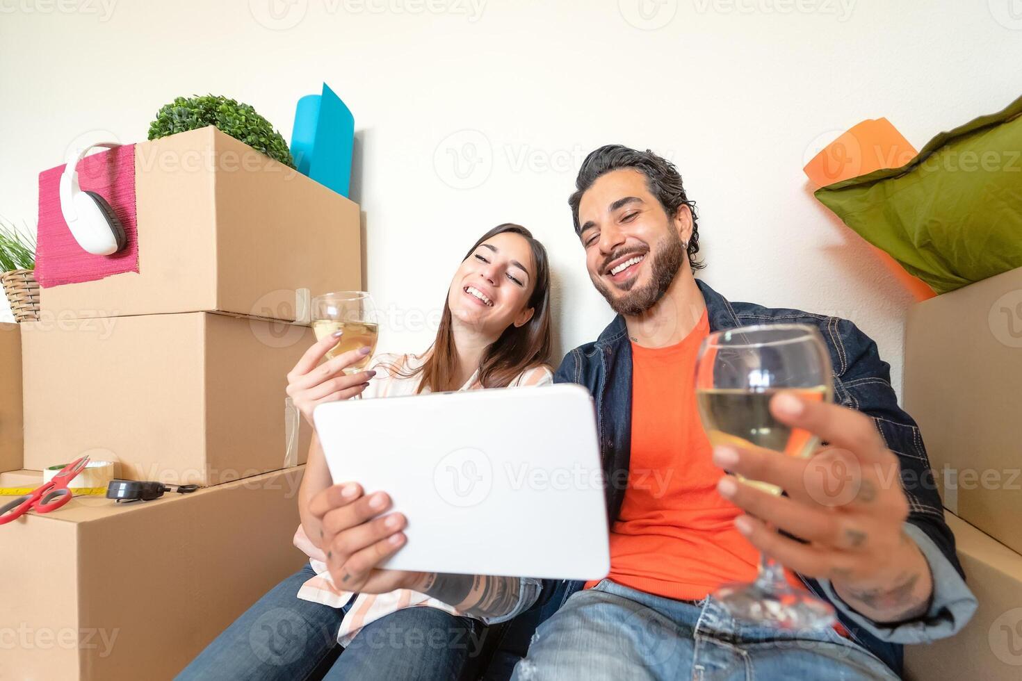 joven Pareja Moviente en nuevo propiedad casa - contento amantes teniendo divertido compras en línea con digital tableta en nuevo hogar - cambio Departamento día y personas relación estilo de vida concepto foto