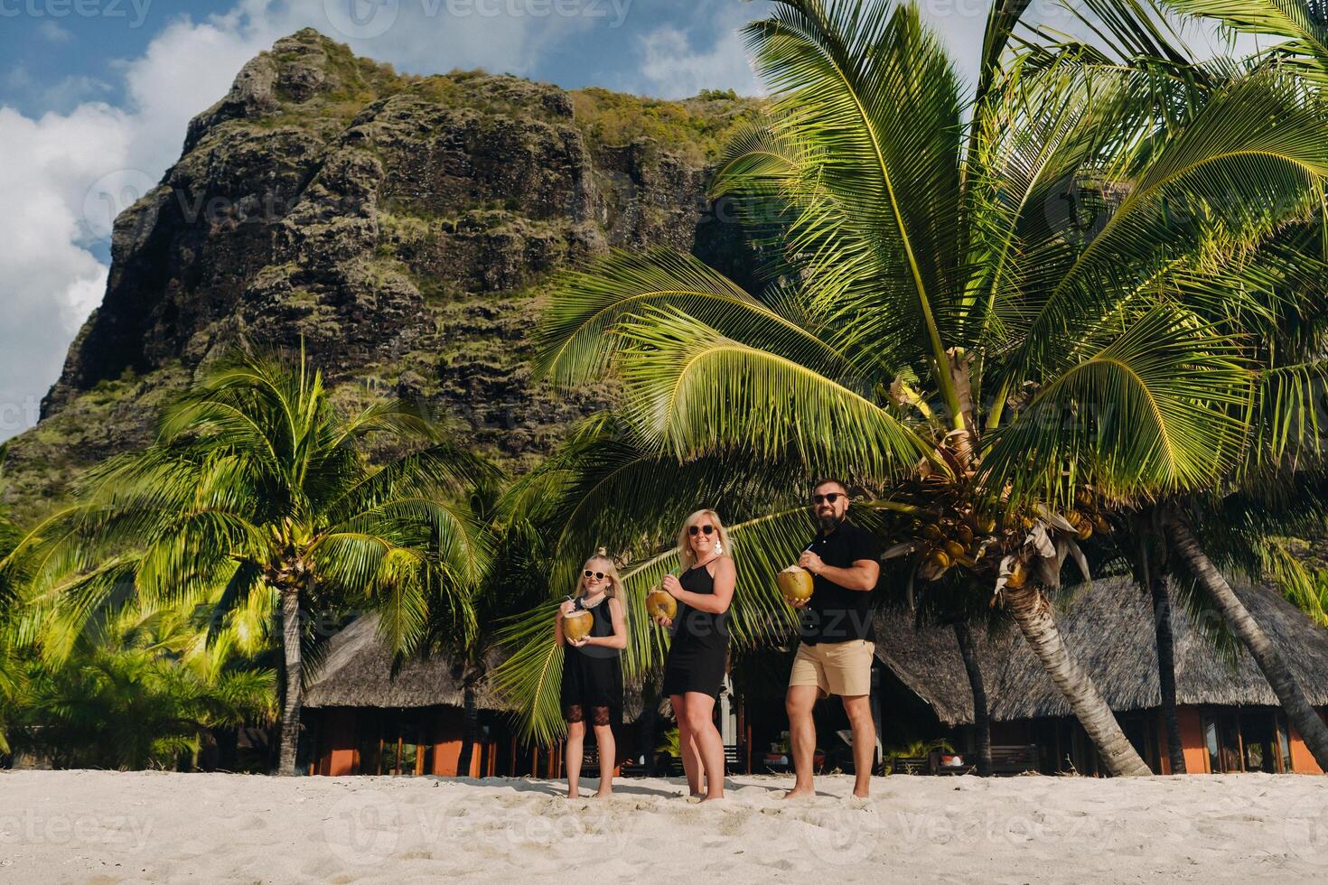 a stylish family in black clothes with coconuts in their hands on the beach of the island of Mauritius.Beautiful family on the island of Mauritius in the Indian ocean photo