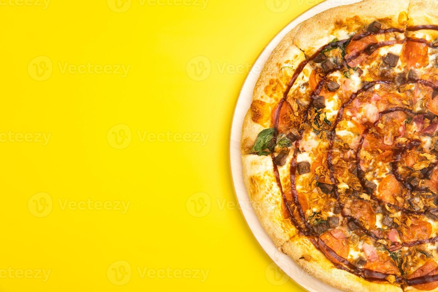 Delicious large pizza with bacon and spinach on a yellow background photo