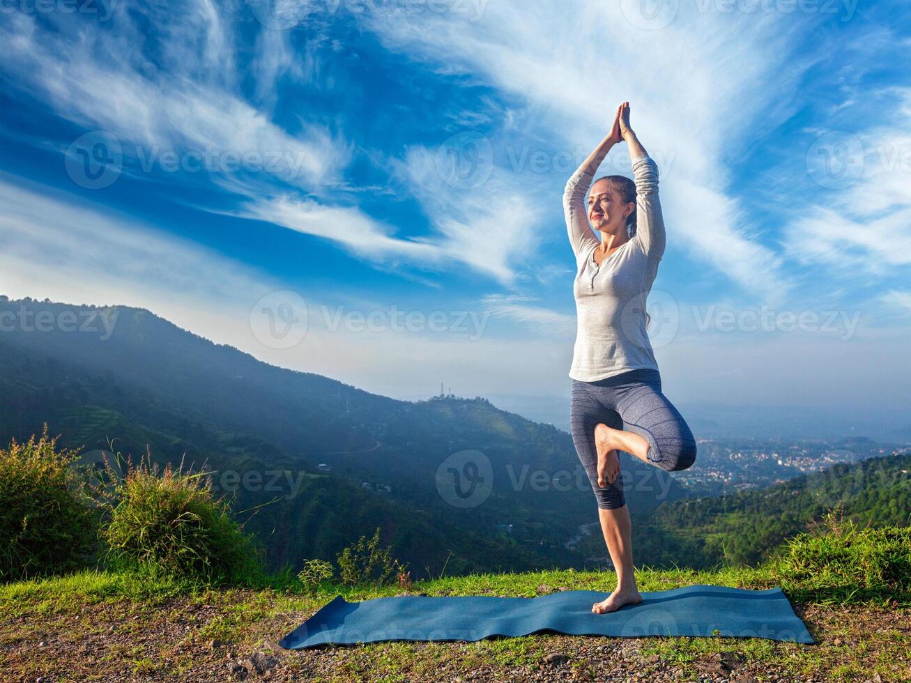 Woman in yoga Vrikshasana tree pose outdoors photo