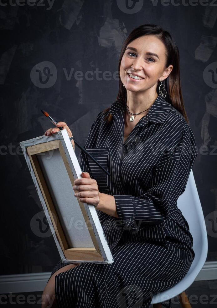 a young brunette female artist stands behind an easel. photo