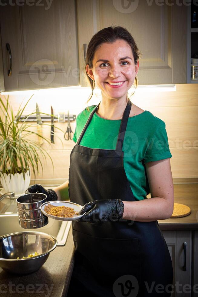 Woman cooking tasty melted chocolate on table in kitchen. photo