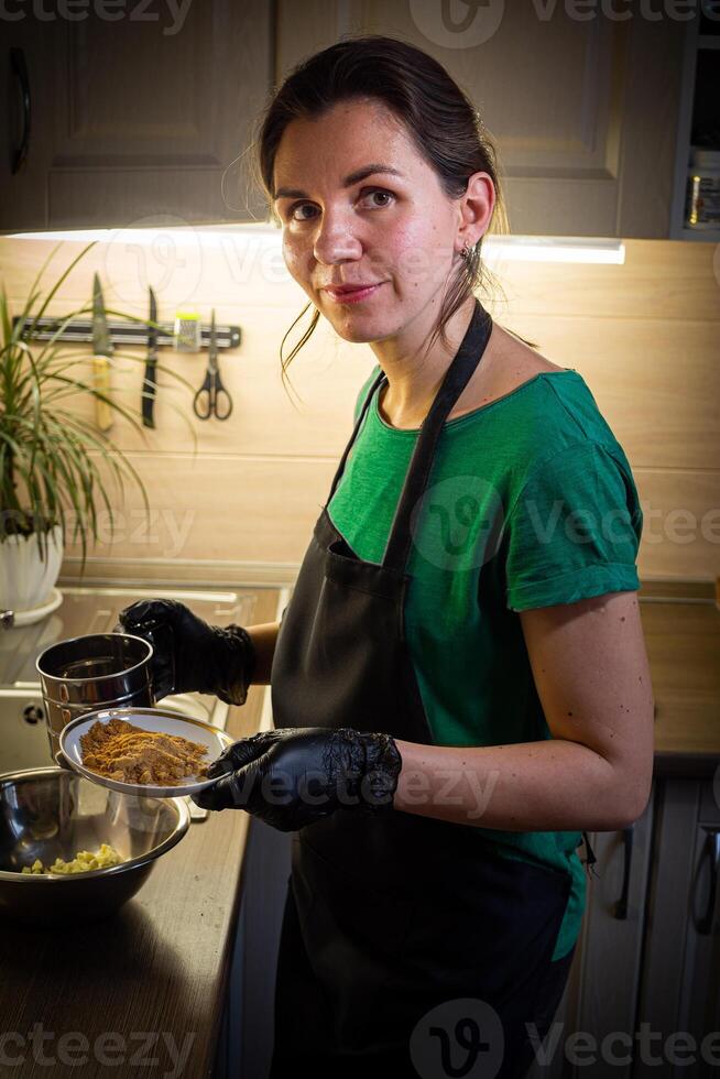 Woman cooking tasty melted chocolate on table in kitchen. photo