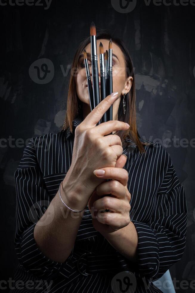 Portrait of a female artist, with brushes in her hands. photo