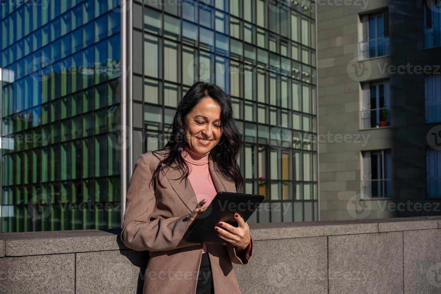 young executive woman answering emails with her digital tablet while smiling photo