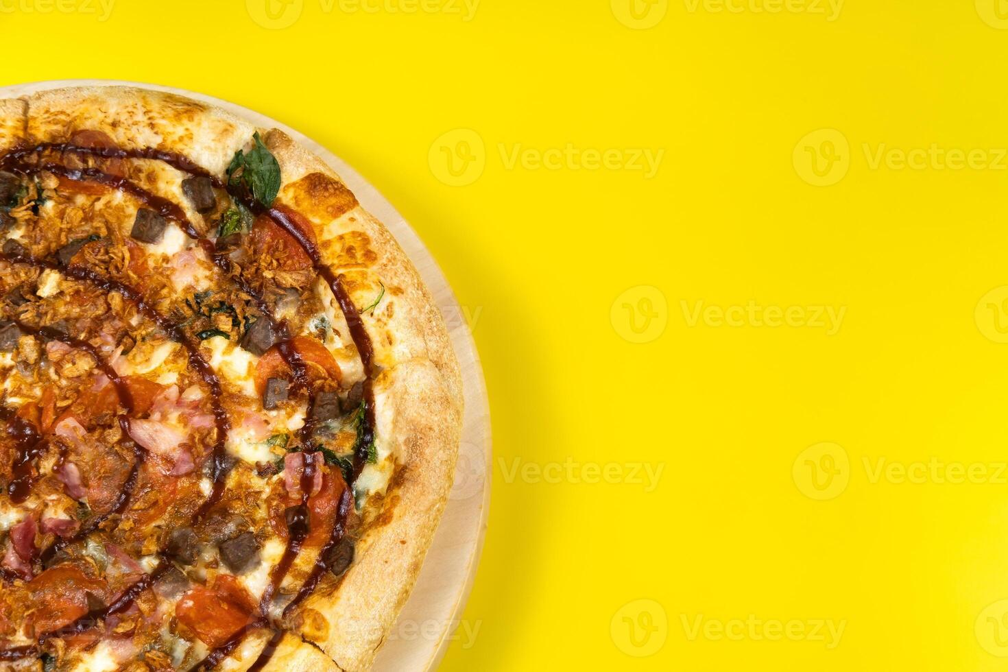 Delicious large pizza with bacon and spinach on a yellow background photo