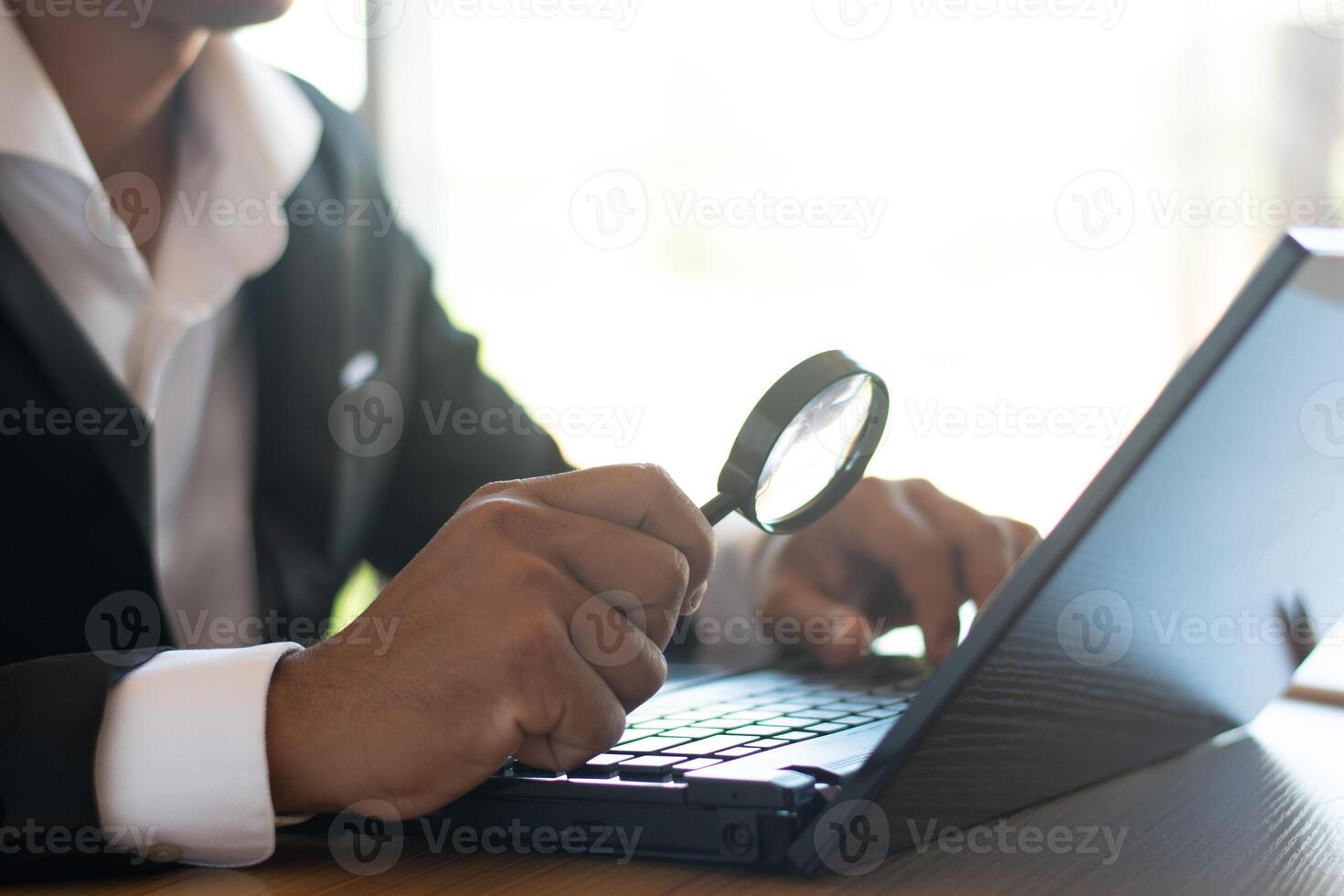 Businessmen or accountants work on computers and use magnifying glasses to view business documents on their desks. photo