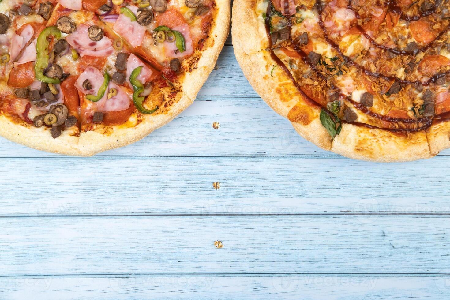 Two different delicious big pizzas on a blue wooden background photo