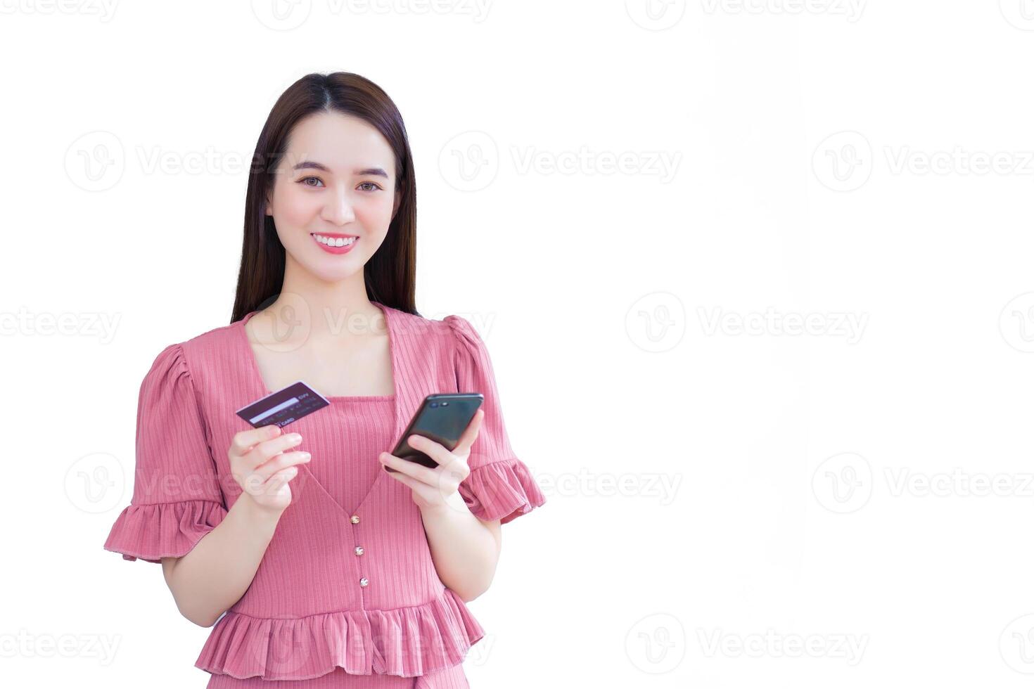 Young asian professional working woman in pink dress successful while holds smartphone and credit card to shop via credit card and mobile banking while isolated white background. photo