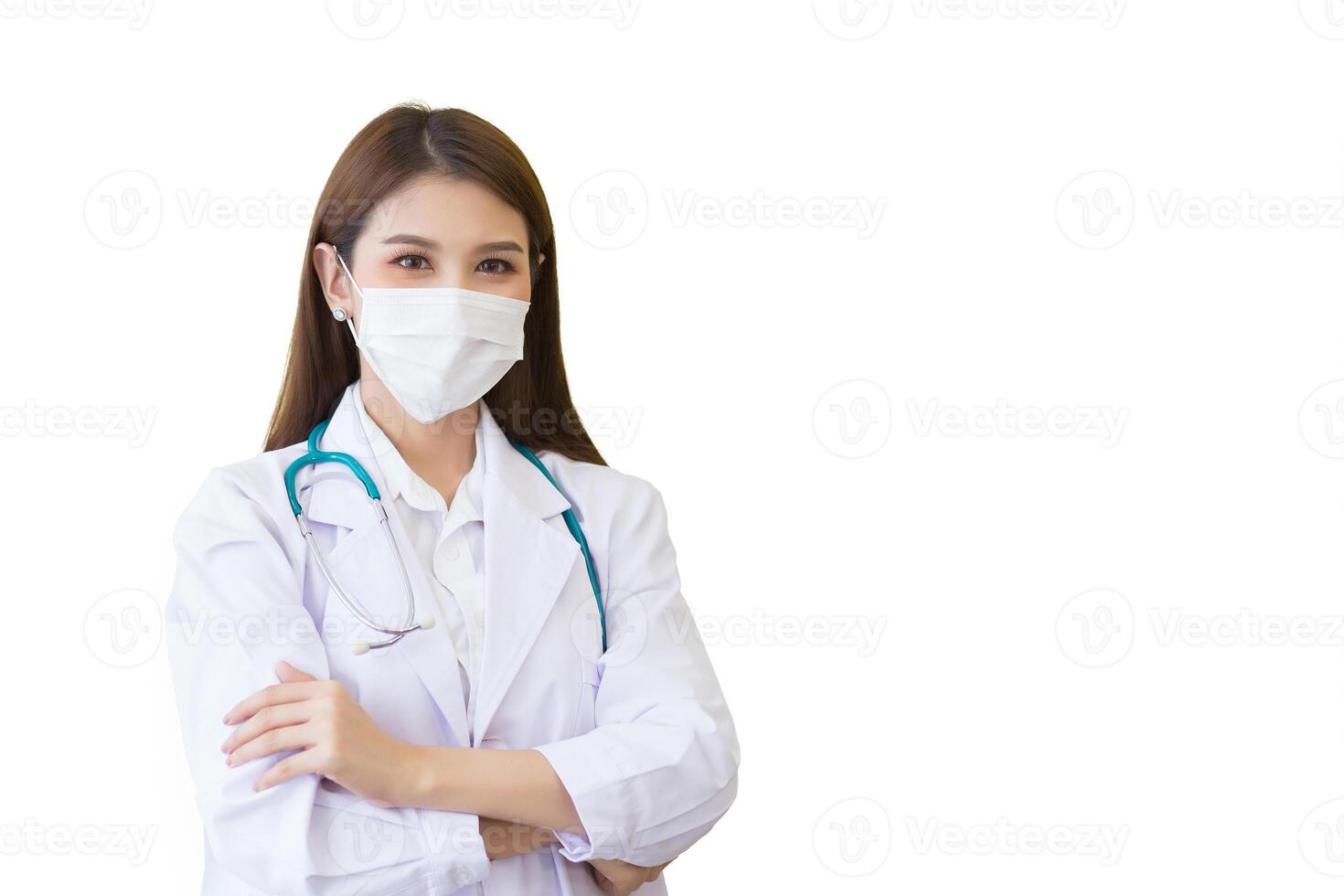 Young professional Asian woman doctor wears medical coat stands confidently and smiles she is arm crossing while she wears white lab coat and face mask in hospital while isolated white background. photo