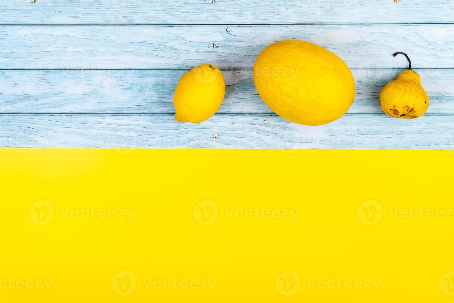 An assortment of yellow fruits lies on a blue wooden background and a yellow background photo