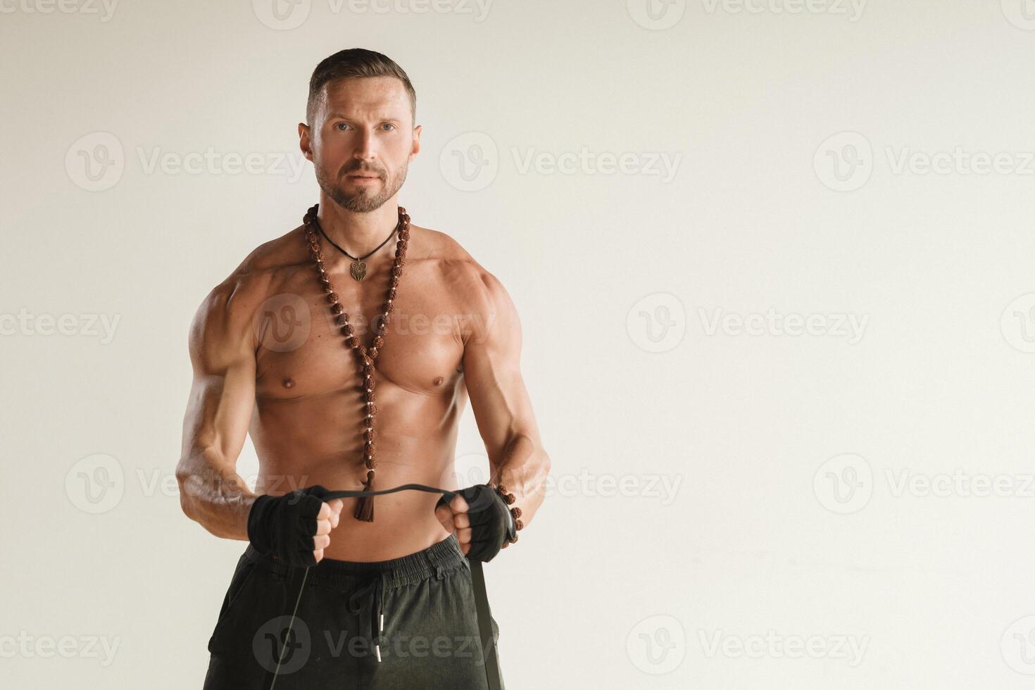 A man with a naked torso is engaged in strength fitness using a rubber loop indoors photo