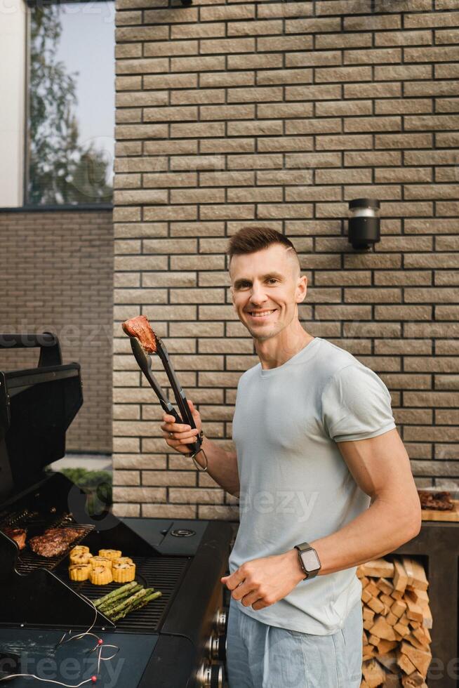 A man on the street is cooking a steak on the grill at a barbecue photo