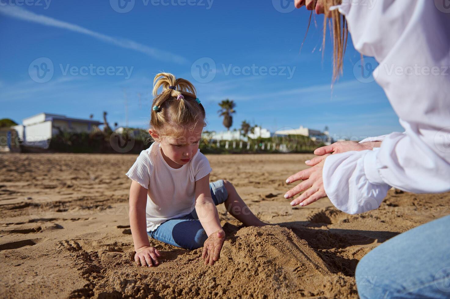 familia construye un arena castillo en el playa en un soleado día, en contra el antecedentes de el mar y el cielo con nubes foto