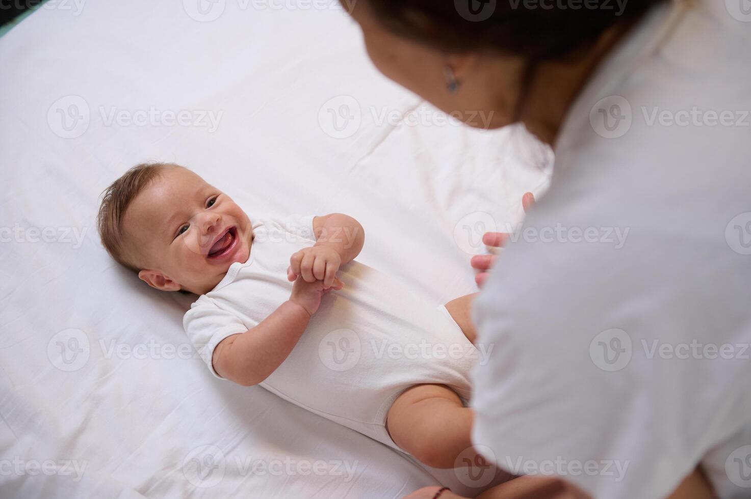 Playful baby boy 4 month old holding hands together, laughing, smiling, catching emotions of his loving caring mother photo