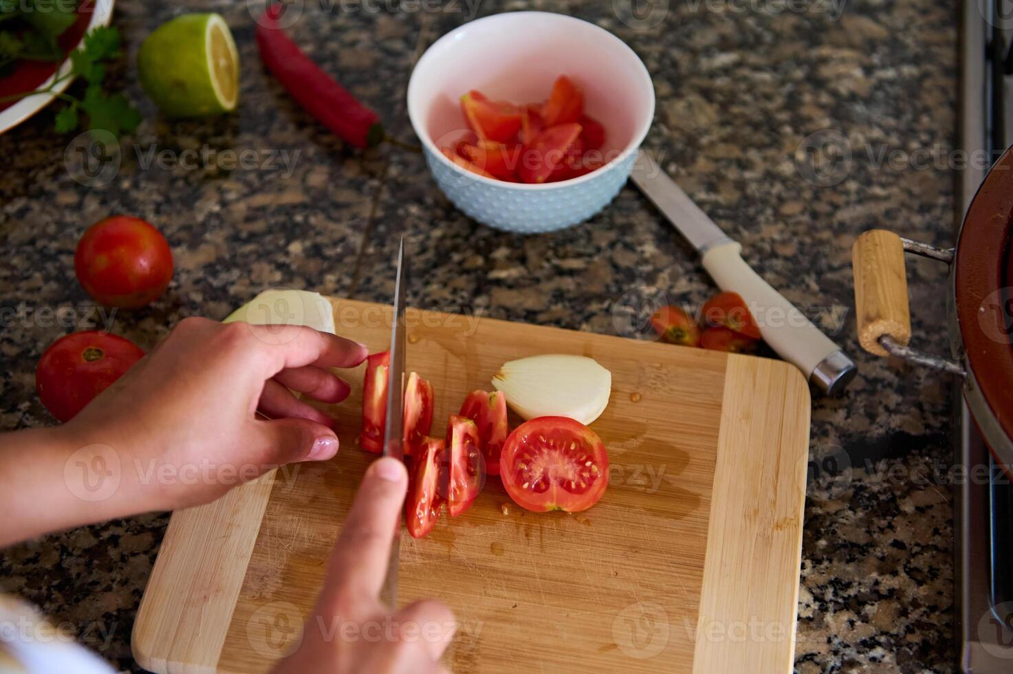 Close-up view from above of a housewife chopping tomatoes on a cutting board photo