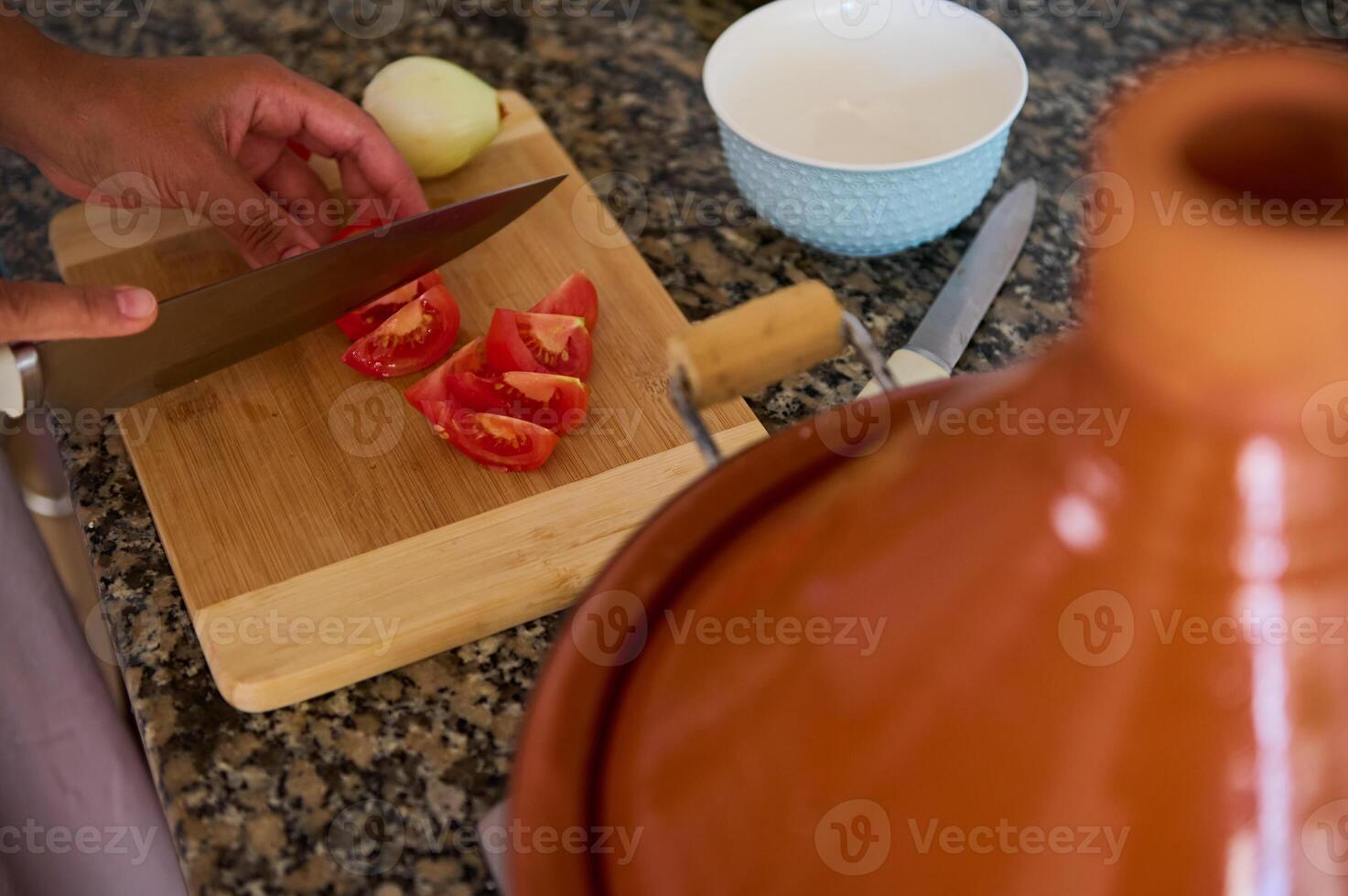 View from above of housewife chopping fresh organic ripe tomatoes on a wooden board while cooking dinner at home photo