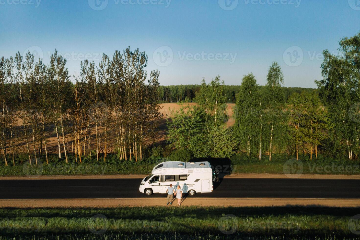 A couple is standing on the road near their motorhome at dawn photo