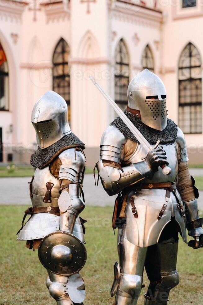 dos caballeros en armadura en el antecedentes de el medieval kossovsky castillo.a medieval concepto.metálico textura foto