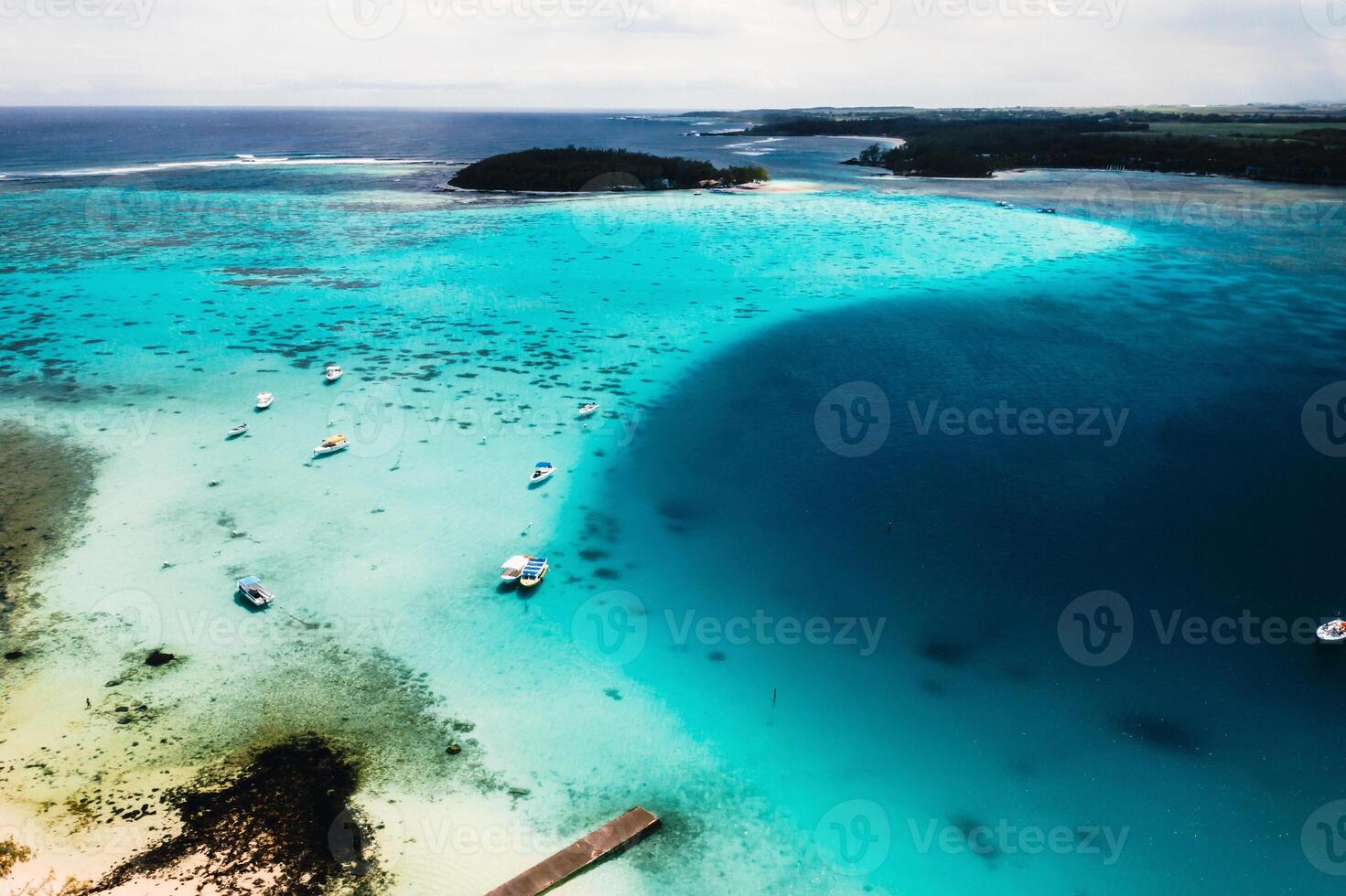 Aerial photography of the East coast of the island of Mauritius. the blue lagoon of the island of Mauritius is shot through from above. The boat is floating on a turquoise lagoon photo
