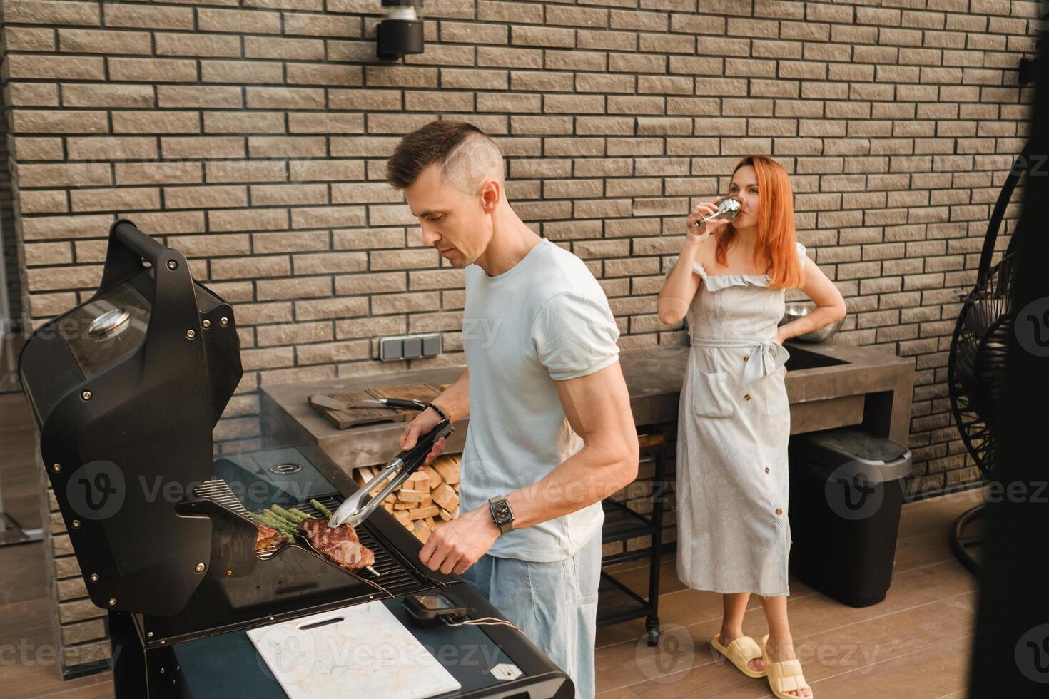 un casado Pareja cocineros A la parrilla carne juntos en su terraza foto