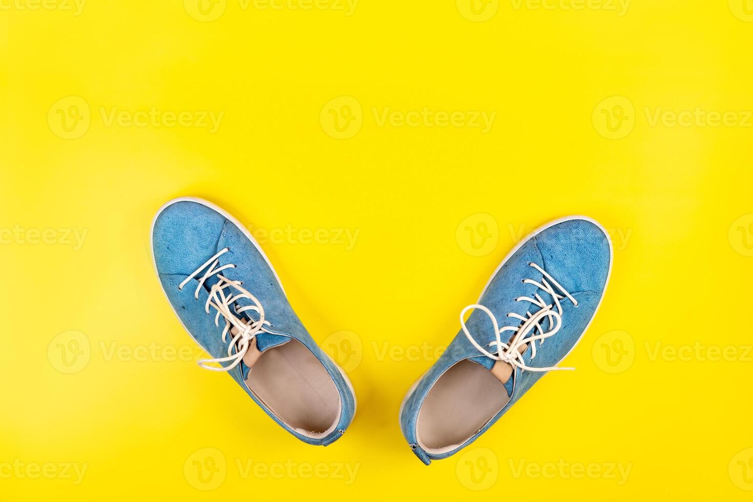 Blue shoes stand on an isolated yellow background photo