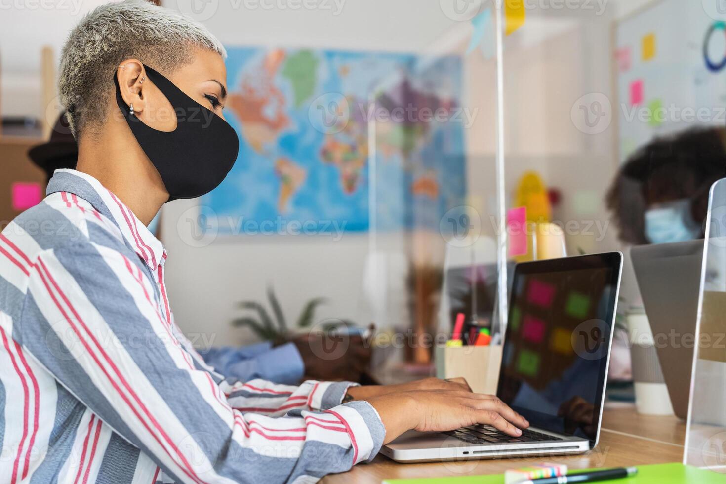Young people in co-working creative space wearing surgical mask and keeping social distance to avoid corona virus spread - Health care and business technology concept photo
