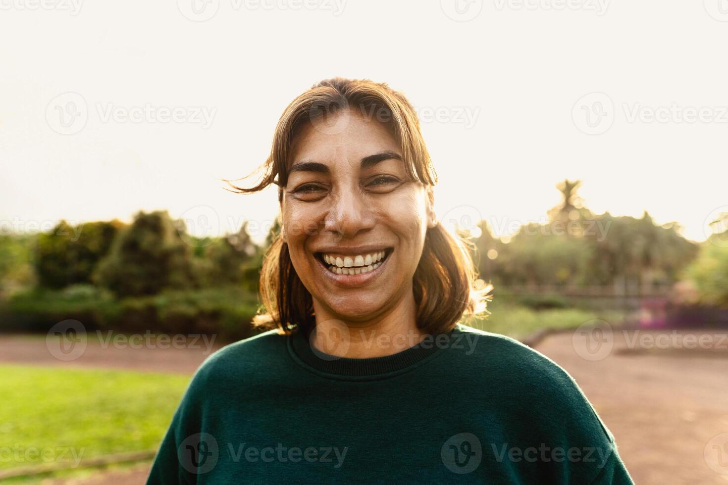 contento latín mujer teniendo divertido sonriente en el cámara en un público parque foto