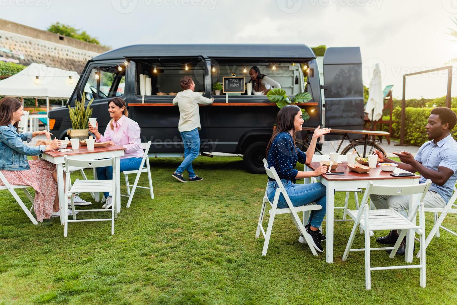 Happy multiracial people having fun eating in a food truck photo