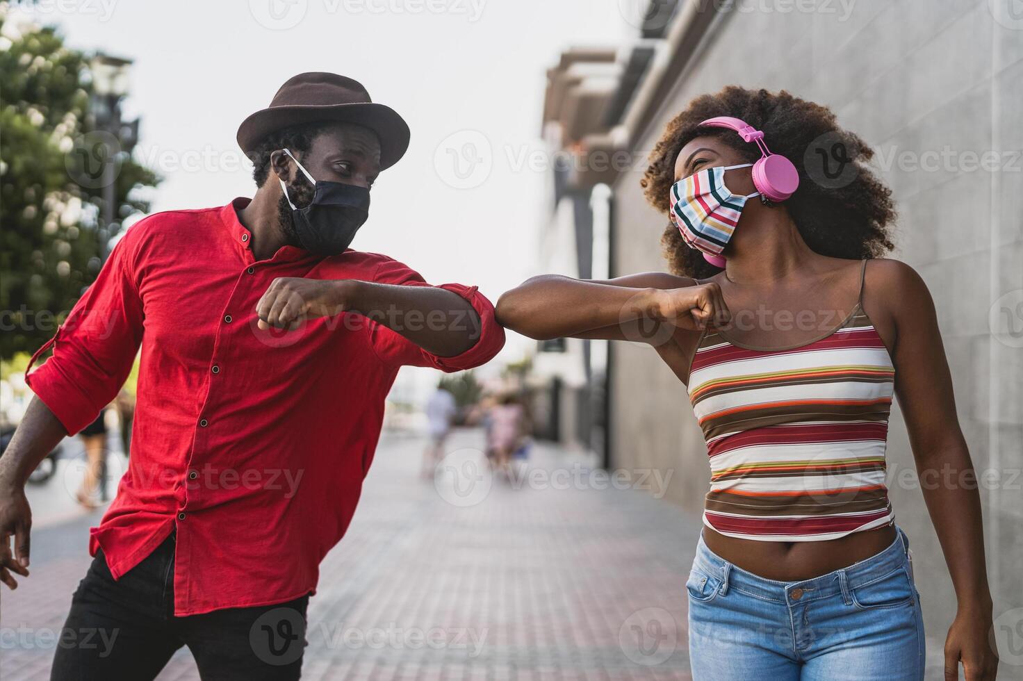 African friends wearing face protective mask while doing new social distance greetings bumping elbows - Youth millennial people and health care guidelines to avoid corona virus spread photo