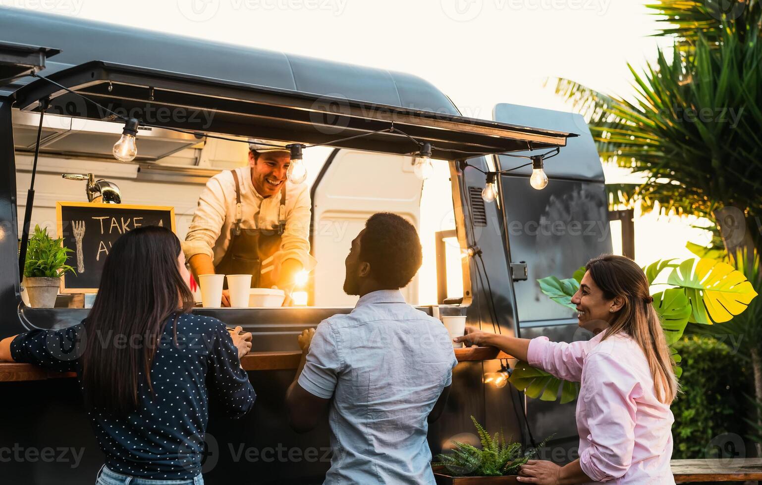 Young people buying meal from street food truck - Modern business and take away concept photo