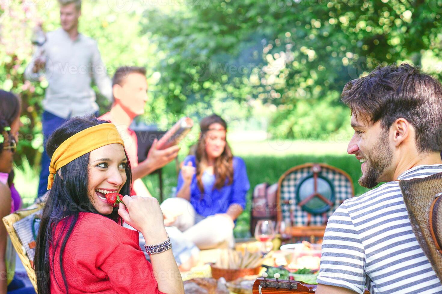 grupo de contento amigos haciendo un picnic barbacoa en un parque al aire libre - joven personas teniendo un parilla fiesta disfrutando comida y bebidas juntos - amistad, estilo de vida, juventud concepto - atención en mujer cara foto