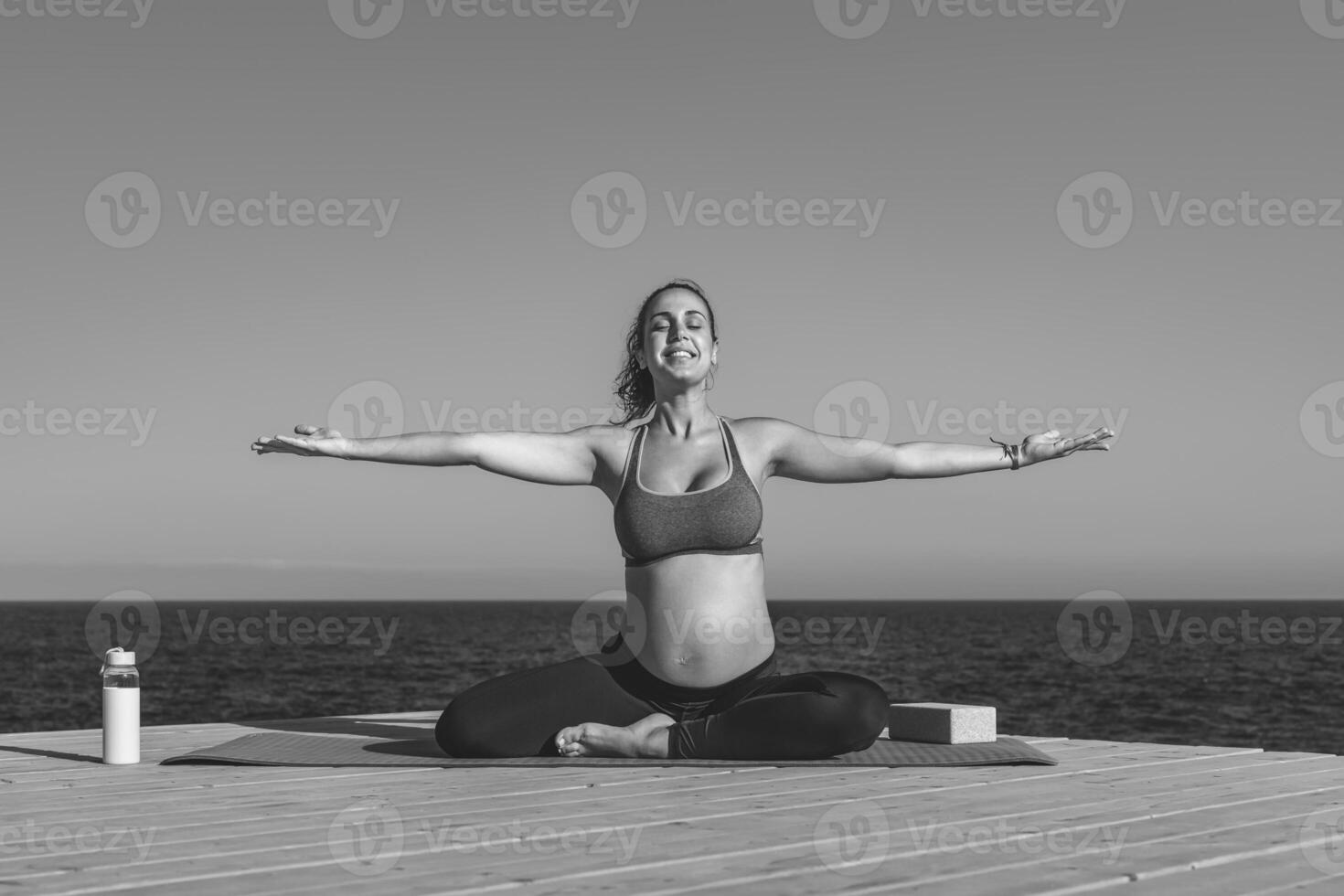 joven embarazada mujer haciendo yoga sesión siguiente el mar - meditación y maternidad concepto - negro y blanco edición foto